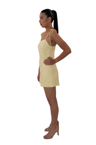 Side view of yellow fitted mini dress with tie shoulders.